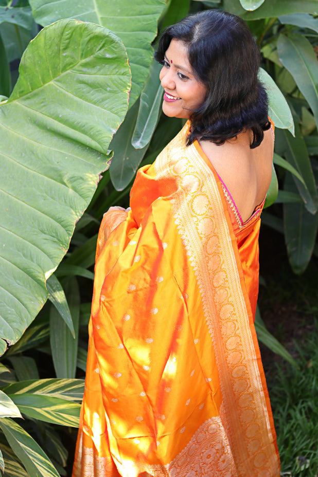 Woman in an orange Benarasi Silk Handloom saree.