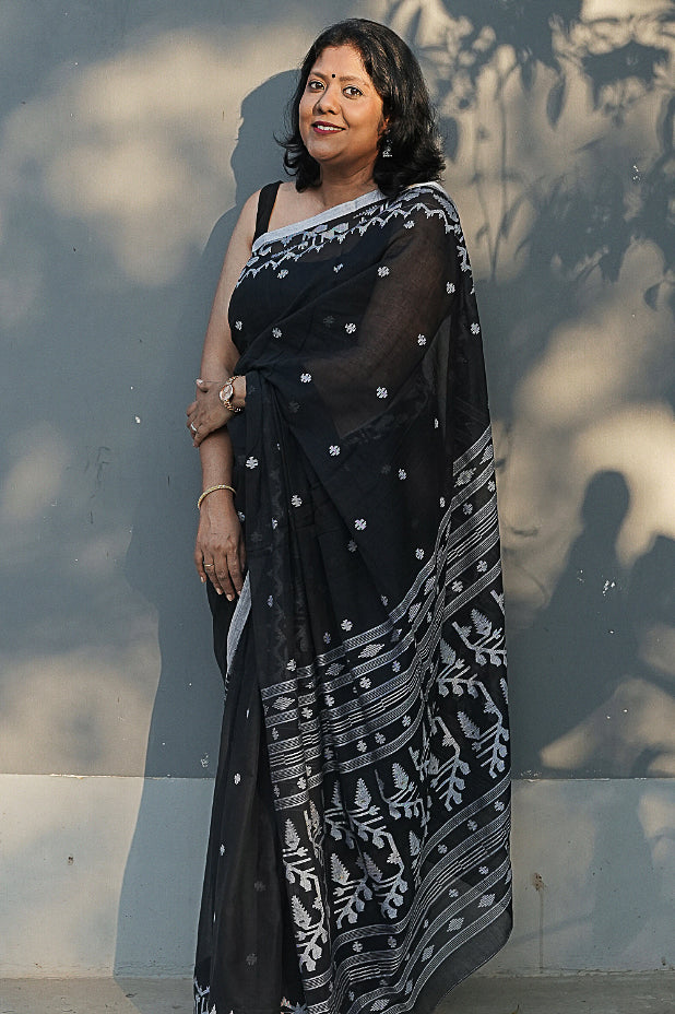 Woman wearing a black Handlooms saree with white Jamdani style patterns.