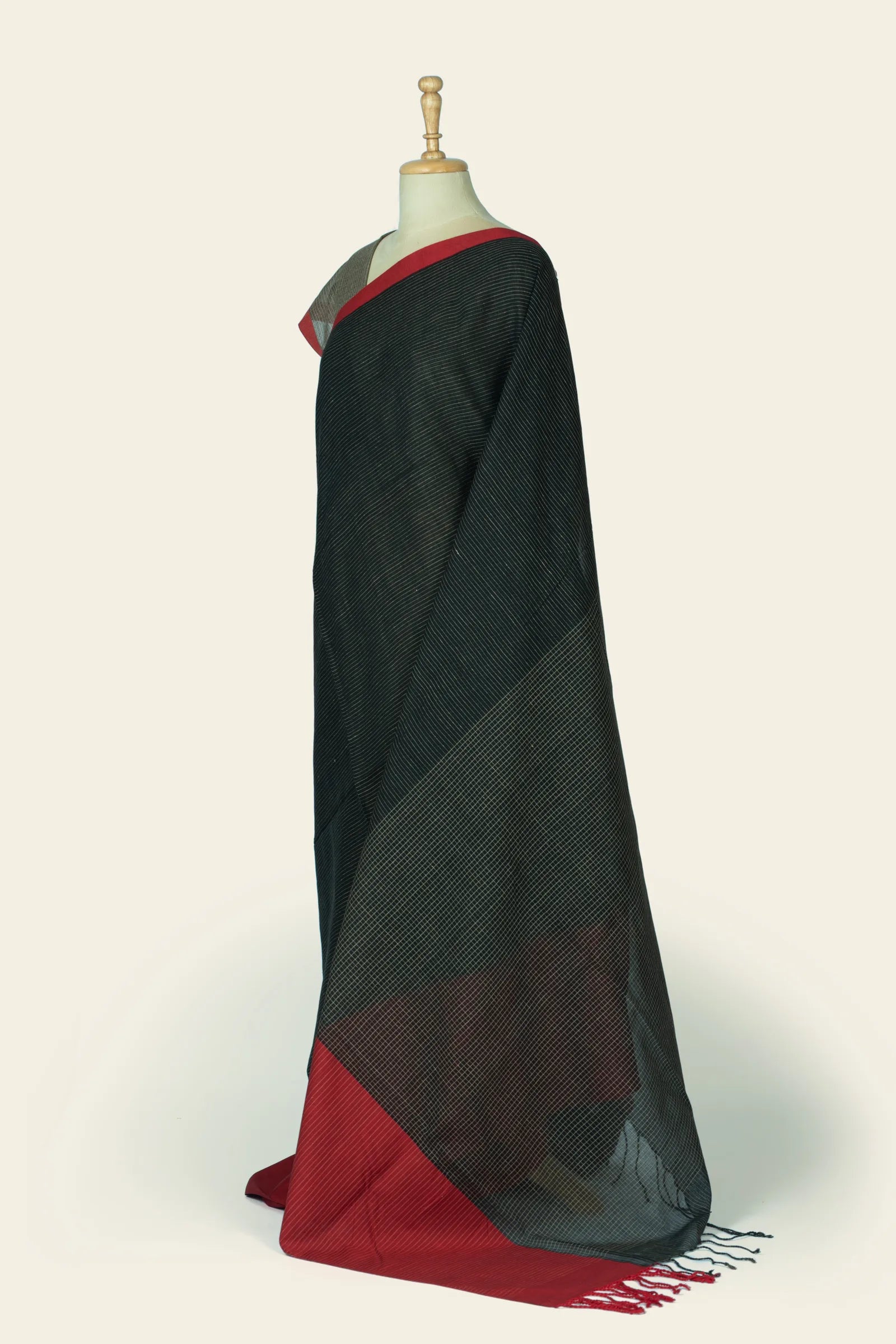 Side-angle of the saree showing the drape and a large triangular pallu section with diamond grid over the black pinstriped body.