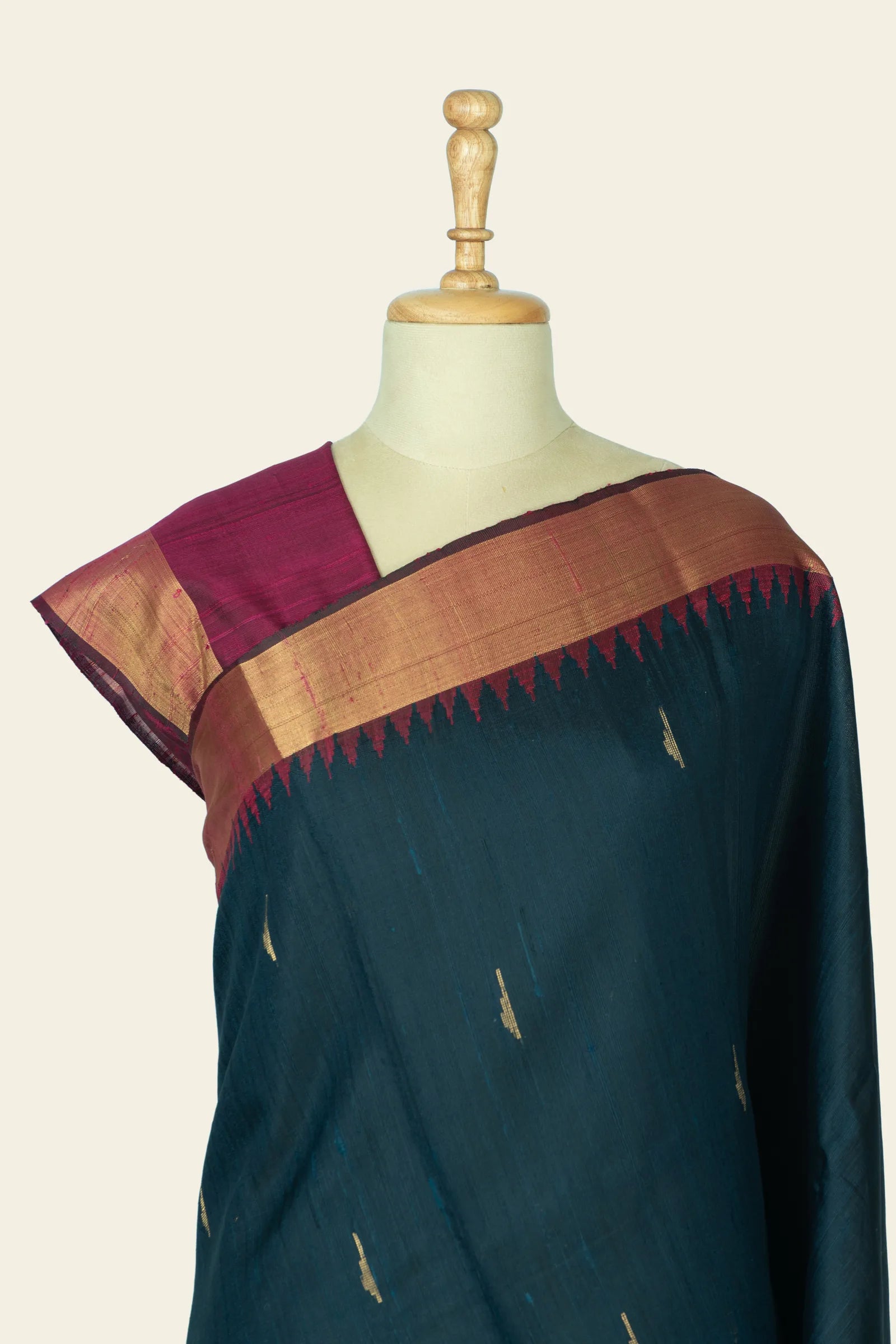 Close front view of the saree on a mannequin highlighting the maroon blouse, gold-bordered pallu edge, and small gold motifs on the body.