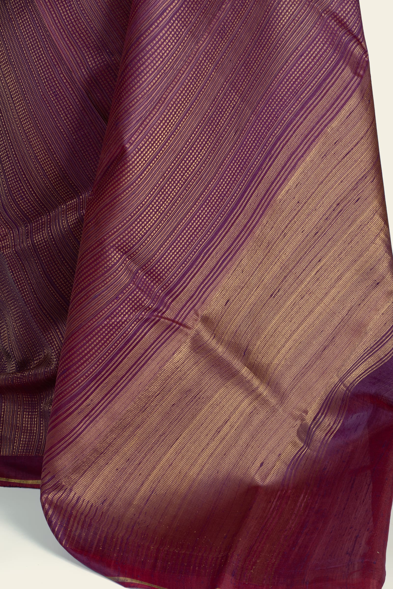 Detailed close-up of the saree's fabric showing dense gold metallic threads forming a fine diagonal stripe and the gold-toned pallu weave.