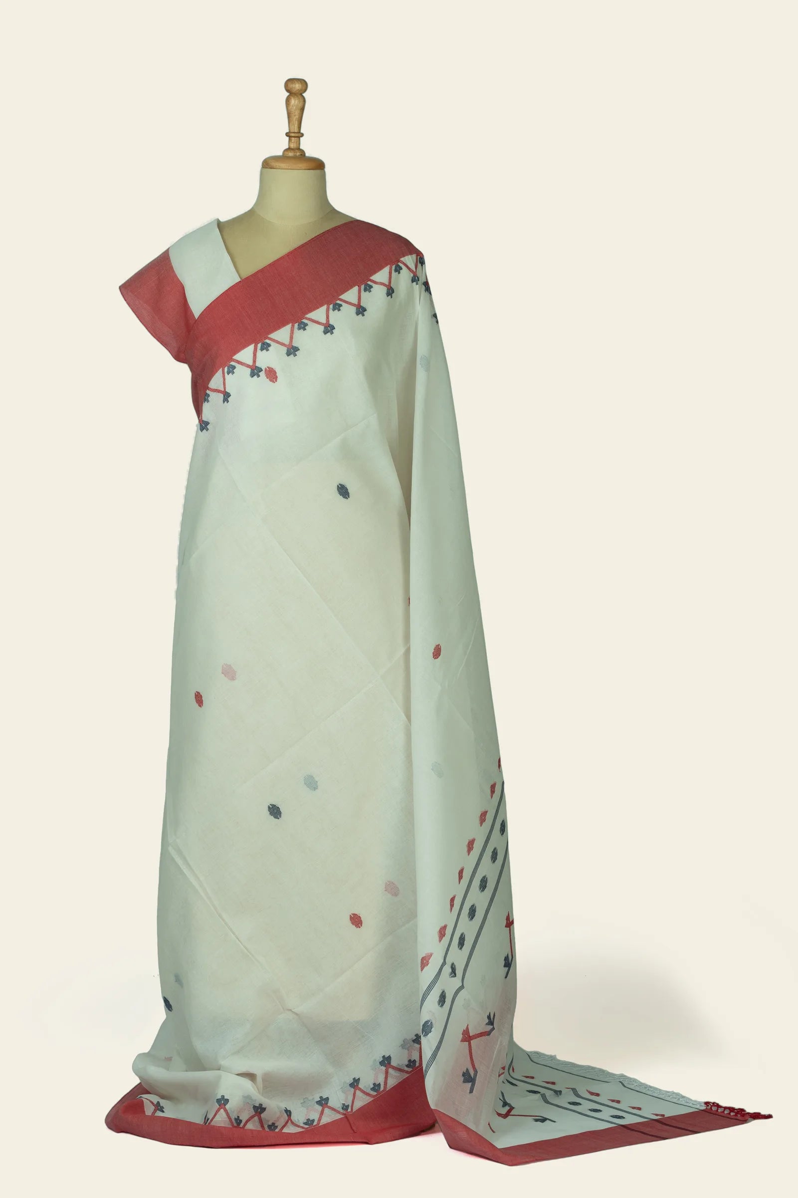 Full-length front drape of an ivory saree with a solid coral border and small scattered dot motifs across the body.
