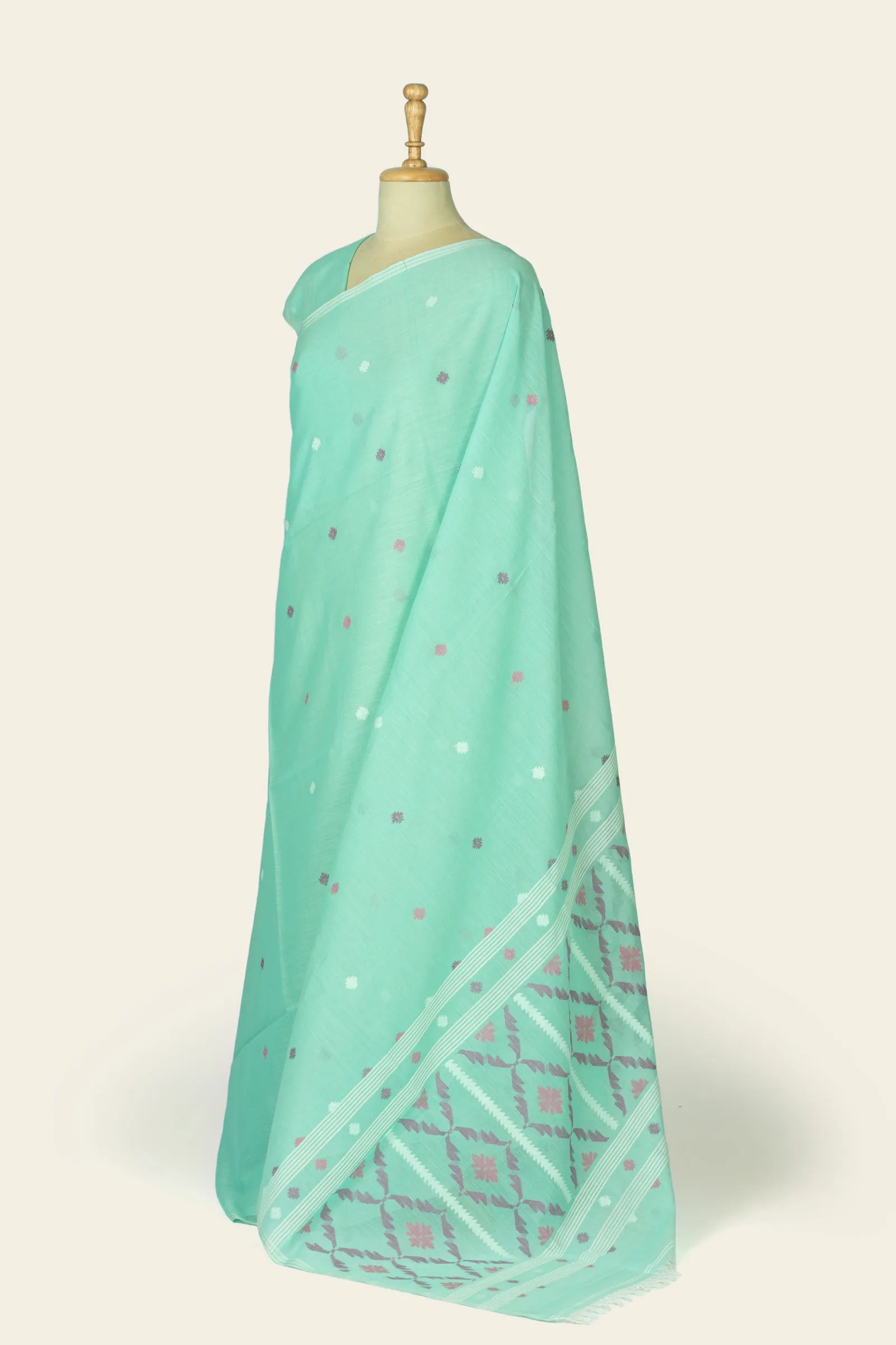 Angled view showing the saree's pallu folded at the hem with geometric motifs and the dotted buta across the body.