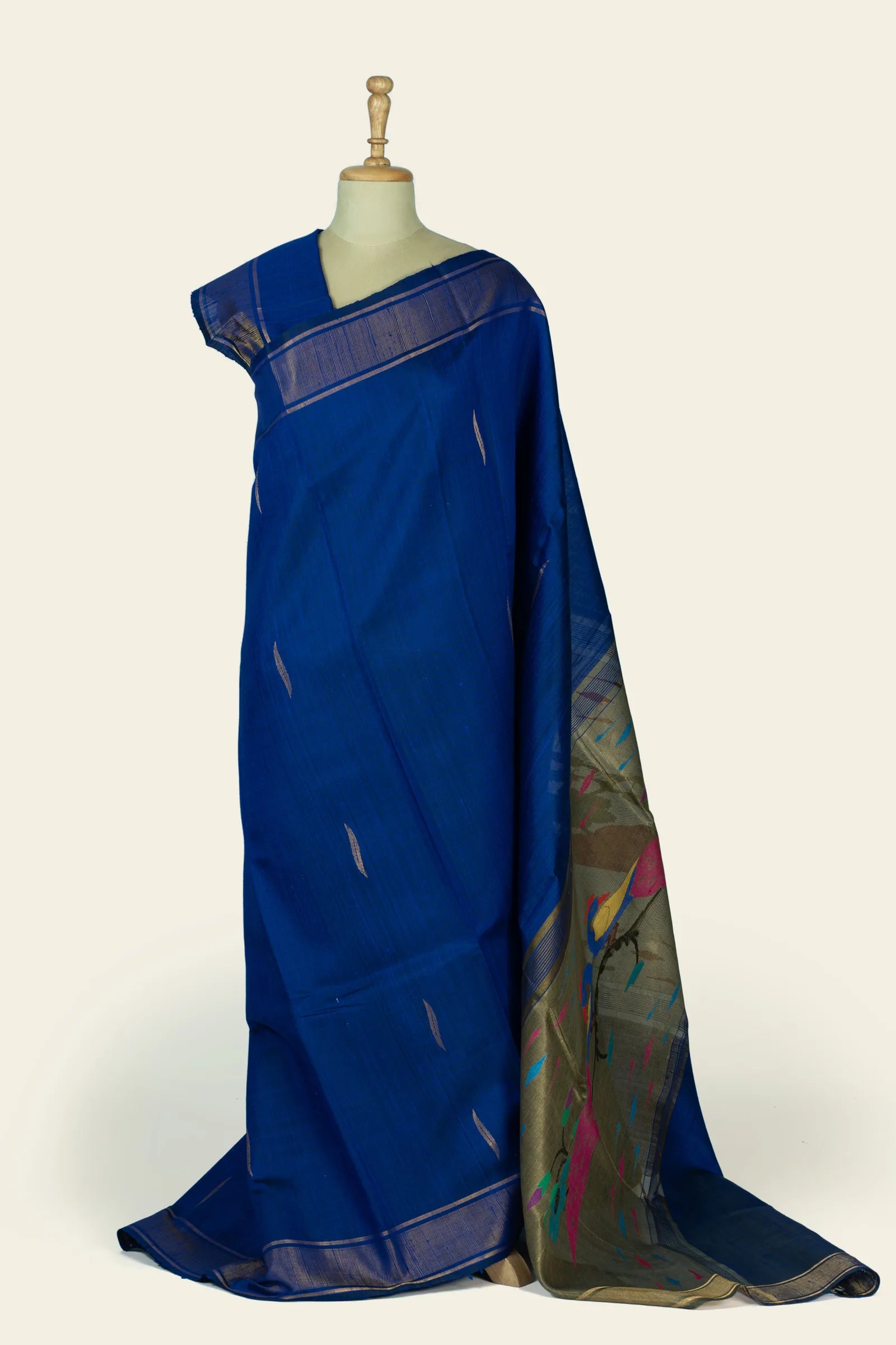 Full-length drape of a deep indigo blue saree on a mannequin showing small leaf-shaped motifs across the body and the pallu folded to reveal an olive-gold panel with colourful bird and floral motifs.