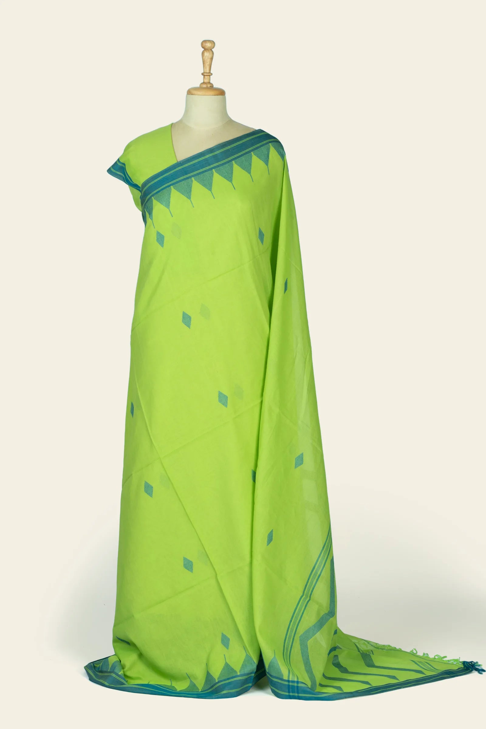 Front drape of a lime green saree shown on a mannequin with teal triangular motifs along the pallu and scattered diamond butis on the body.