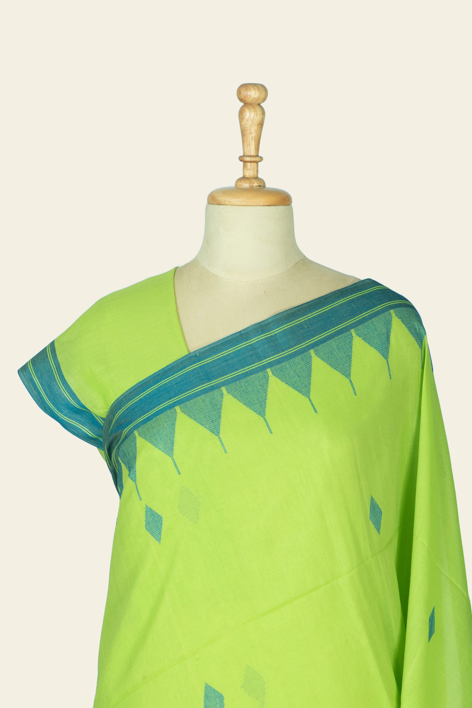 Close cropped view of the saree at the shoulder and neckline showing the teal woven border and triangular motif repeat.