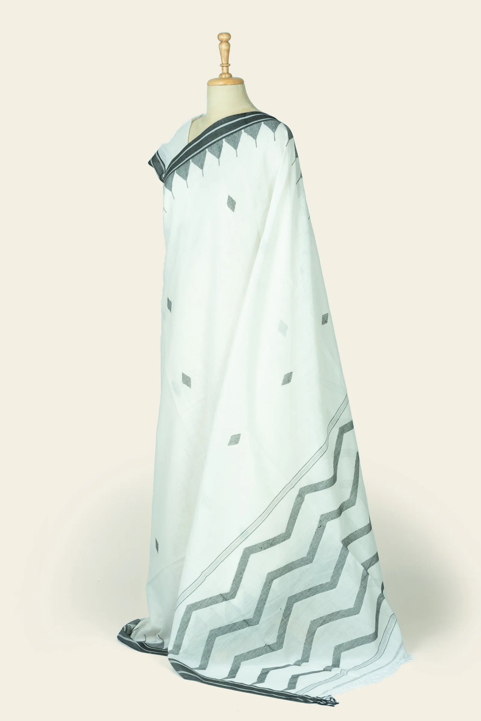 Angled three-quarter view showing the saree's body with diamond butis and the pallu's wide zigzag border.