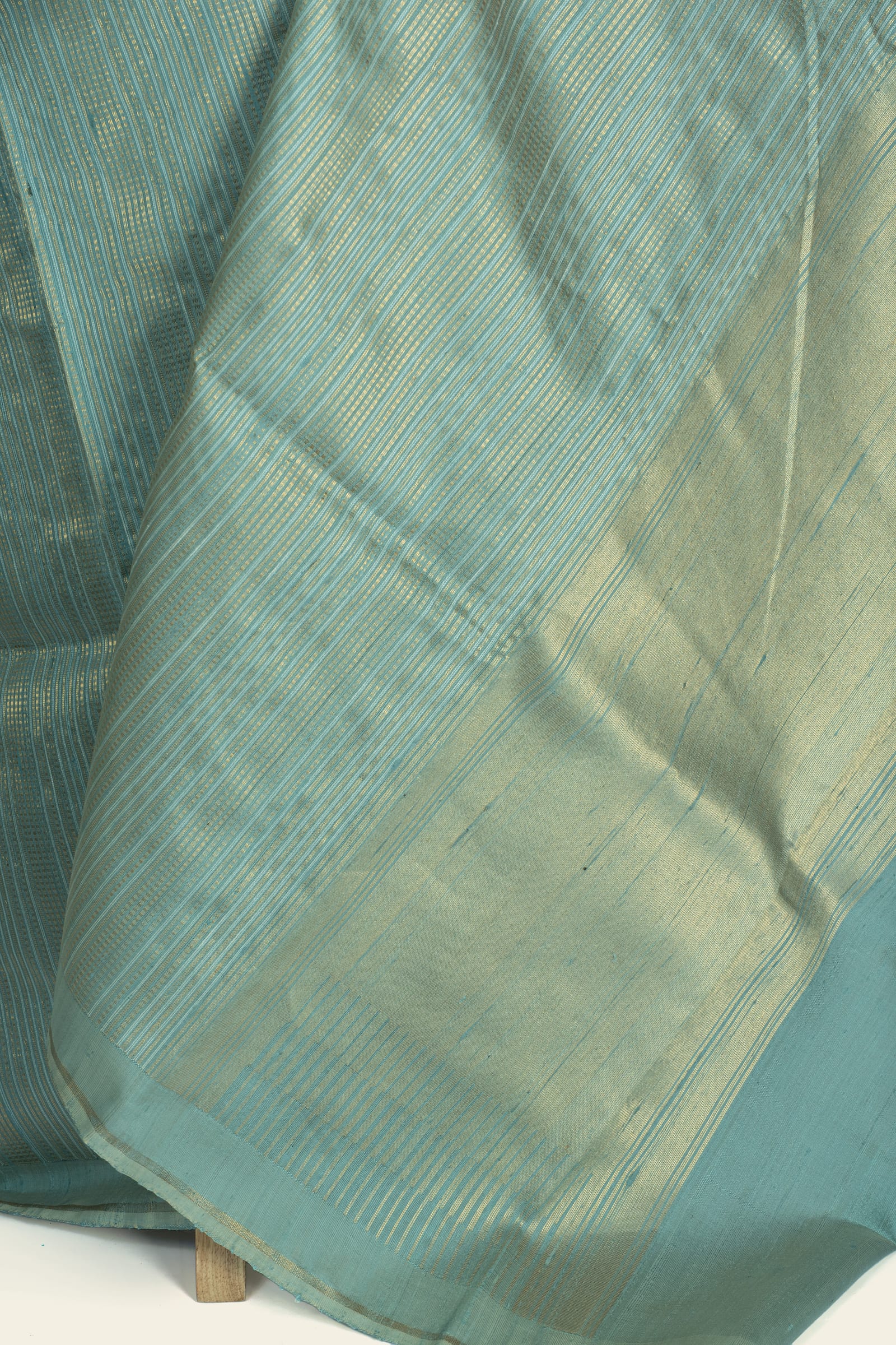 Close-up of the saree pallu showing dense gold stripes and the gold-washed panel.