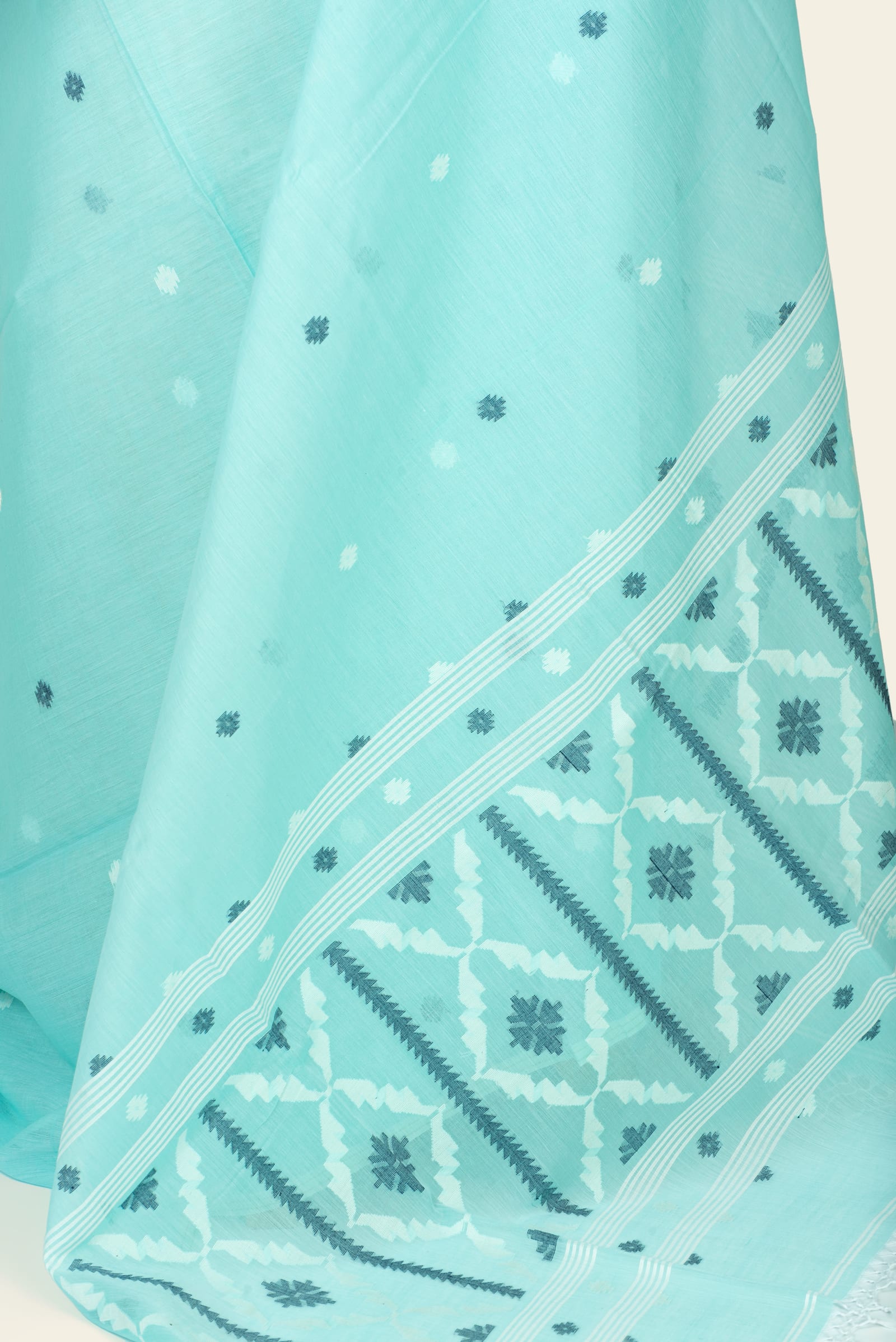 Detail of the saree pallu showing a repeating geometric block pattern with striped separators and scattered dot motifs on the body.
