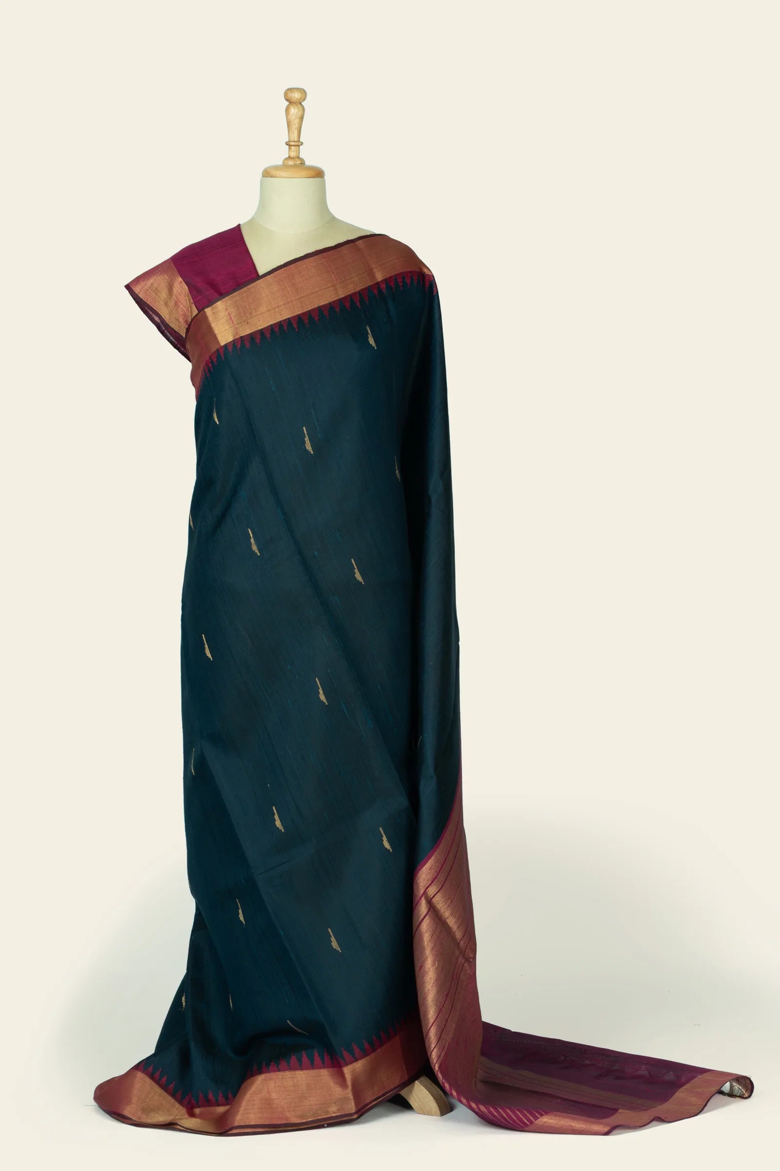 Full drape view of a deep indigo-blue saree with scattered small gold motifs, a maroon and gold border, and a maroon pallu peeking on the floor.
