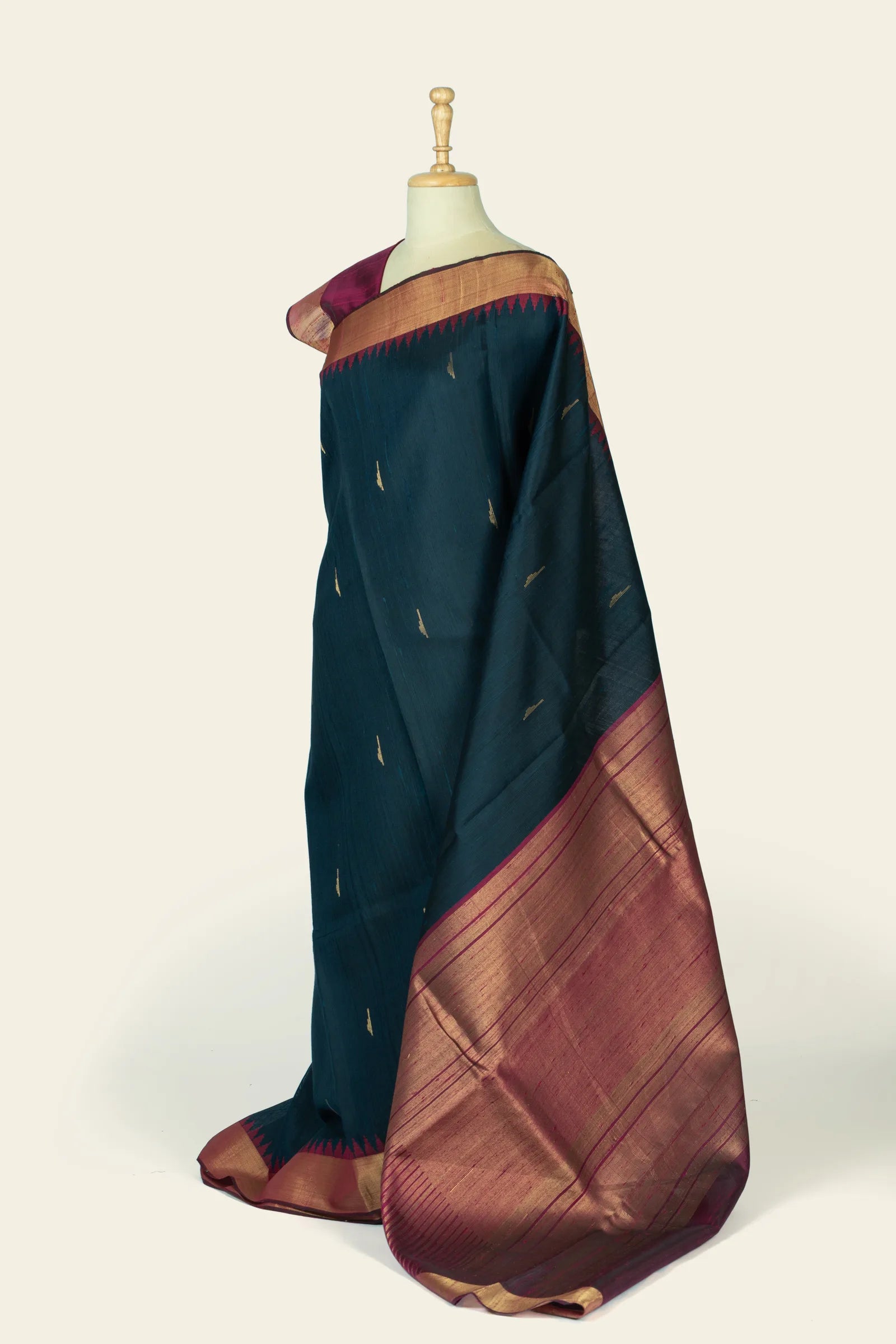Side view showing the saree's indigo body and a wide maroon-gold pallu with horizontal zari lines.