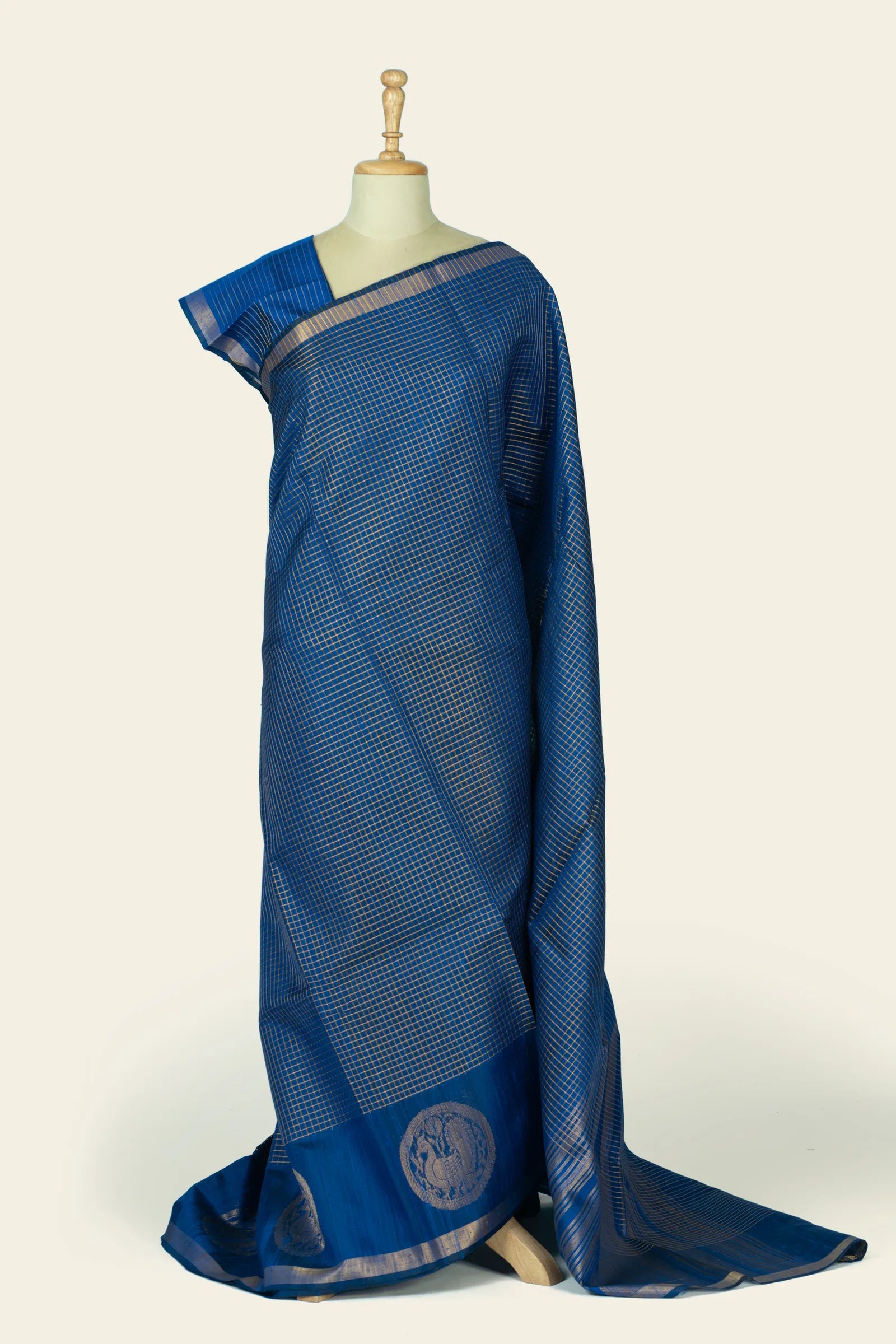 Full-body front drape of an indigo blue saree on a mannequin showing an all-over small checked grid and the lower border with circular medallion motifs.