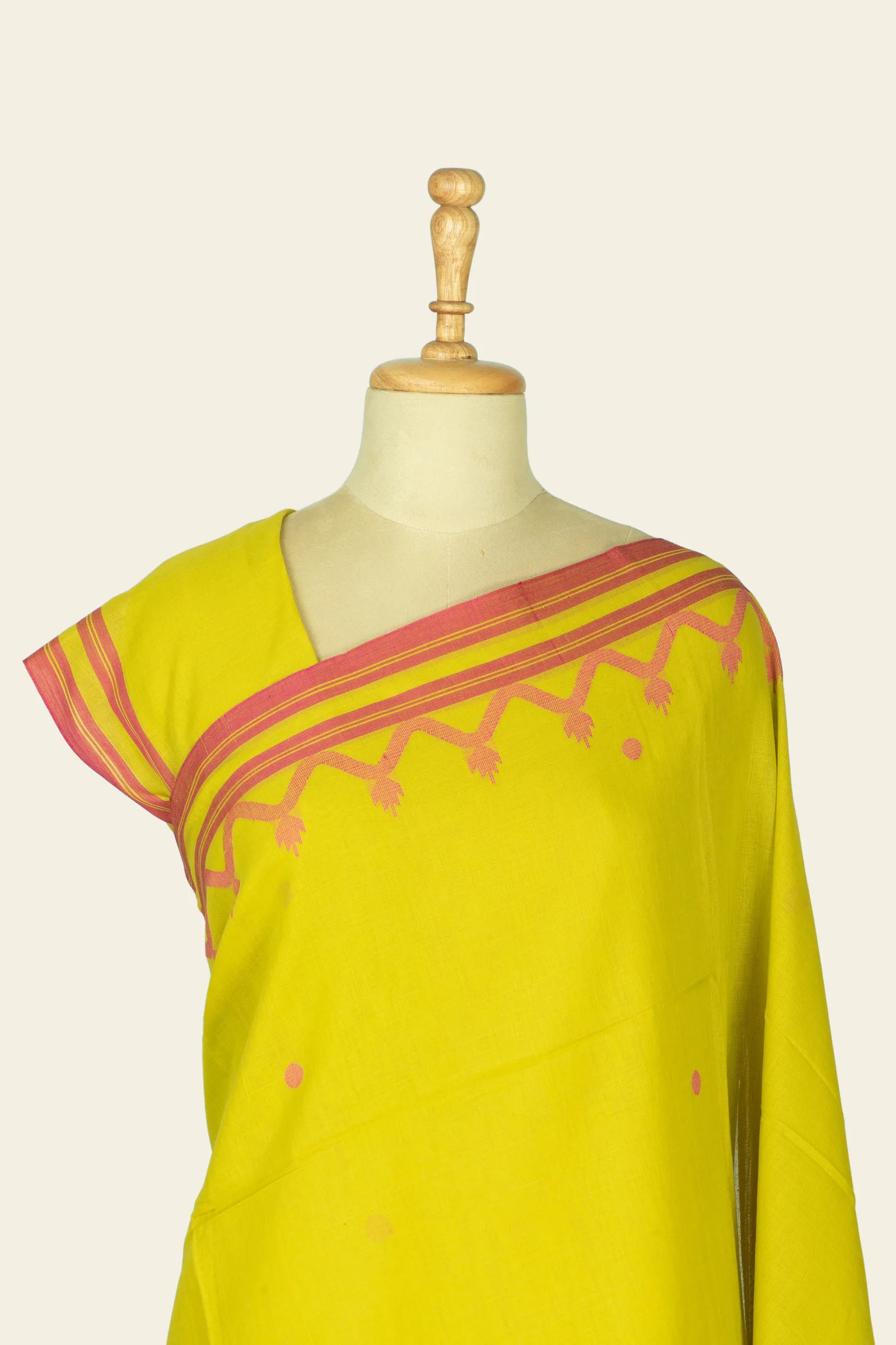 Close shot of the mannequin neckline showing the pink striped border at the saree edge and small round pink motifs on the body.