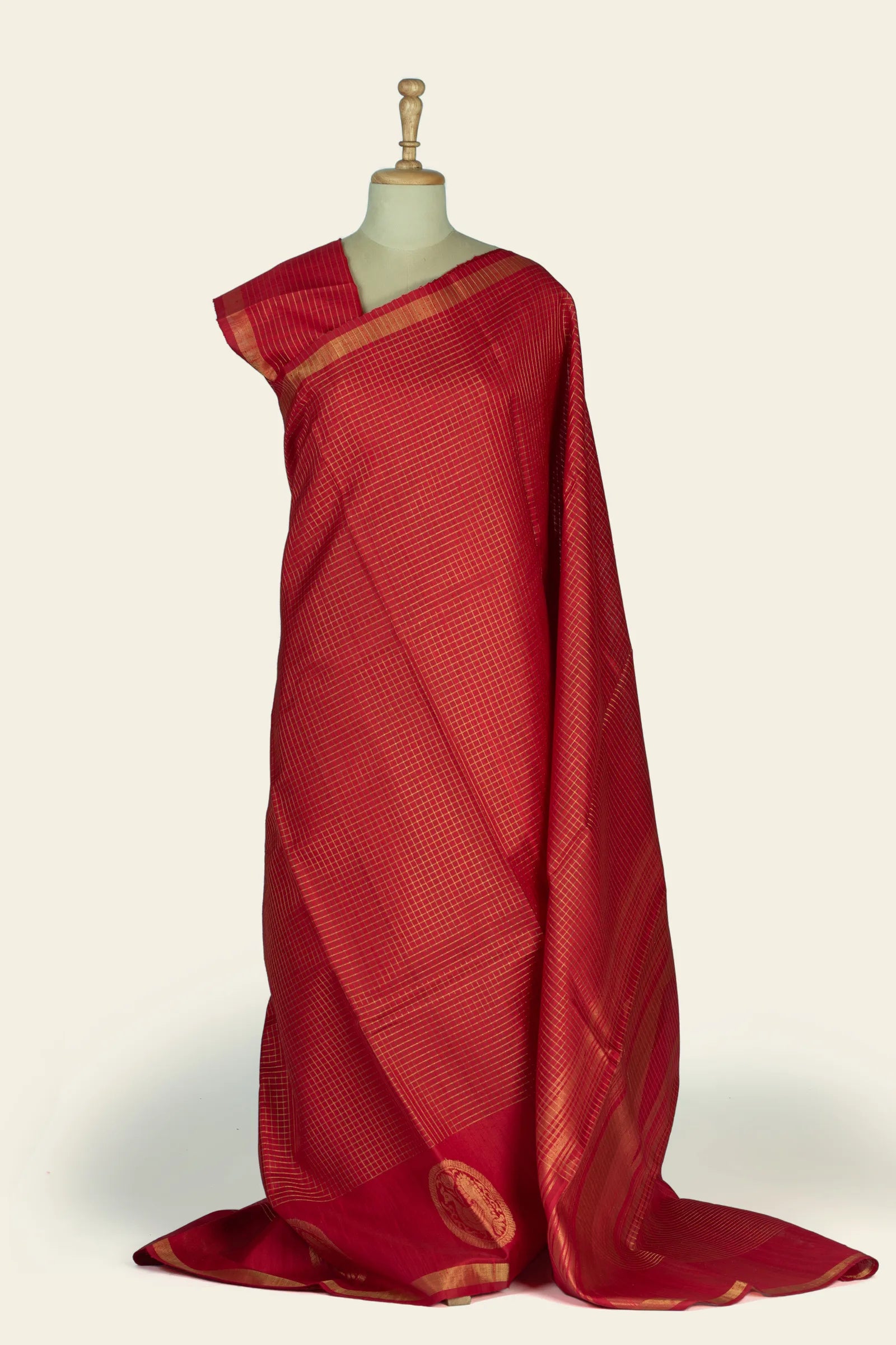 Full drape view of a red saree with an all-over fine gold checked grid and a gold-bordered pallu, shown on a mannequin.