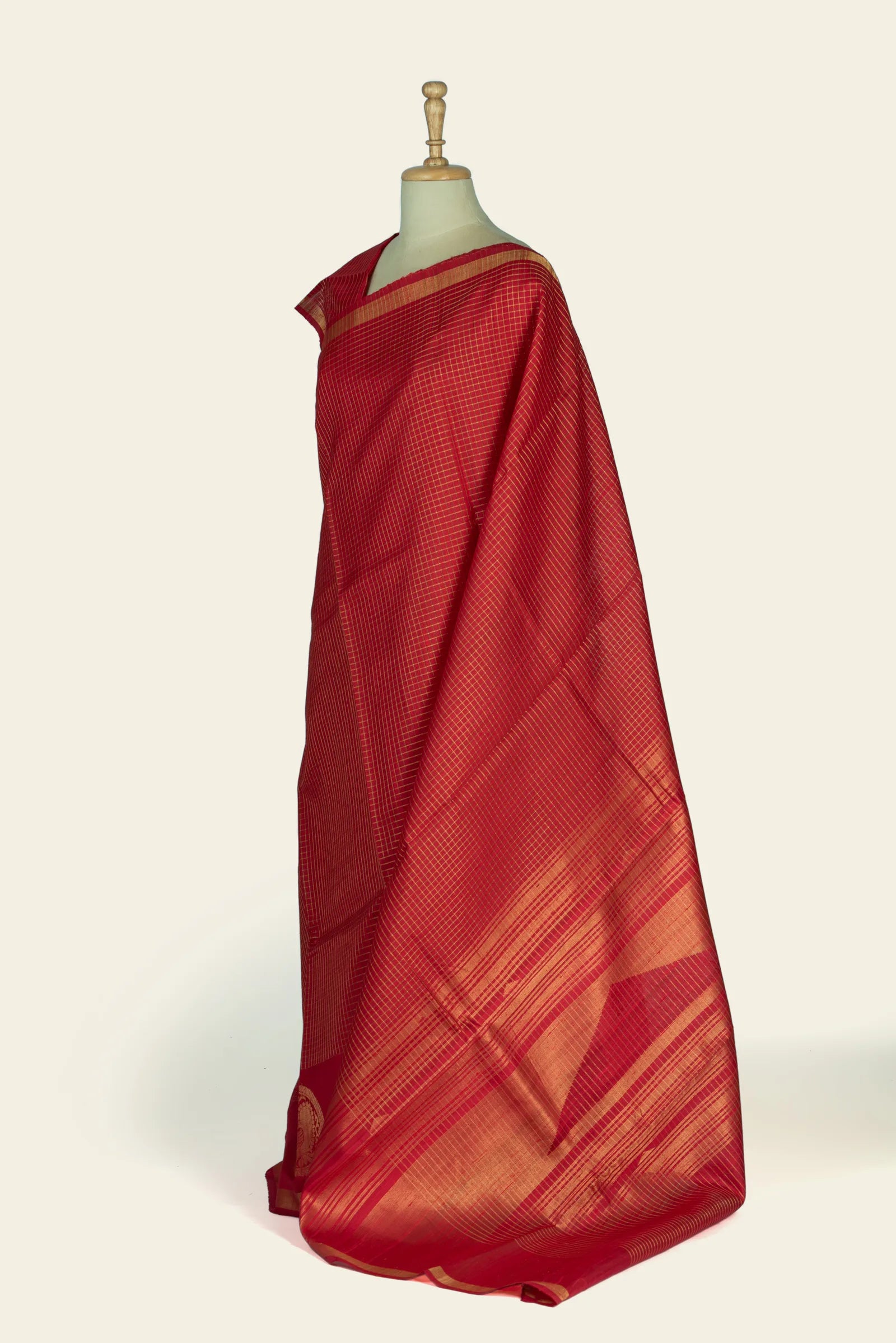 Side view showing the saree's pallu in gold stripes and a red base with checked weave.