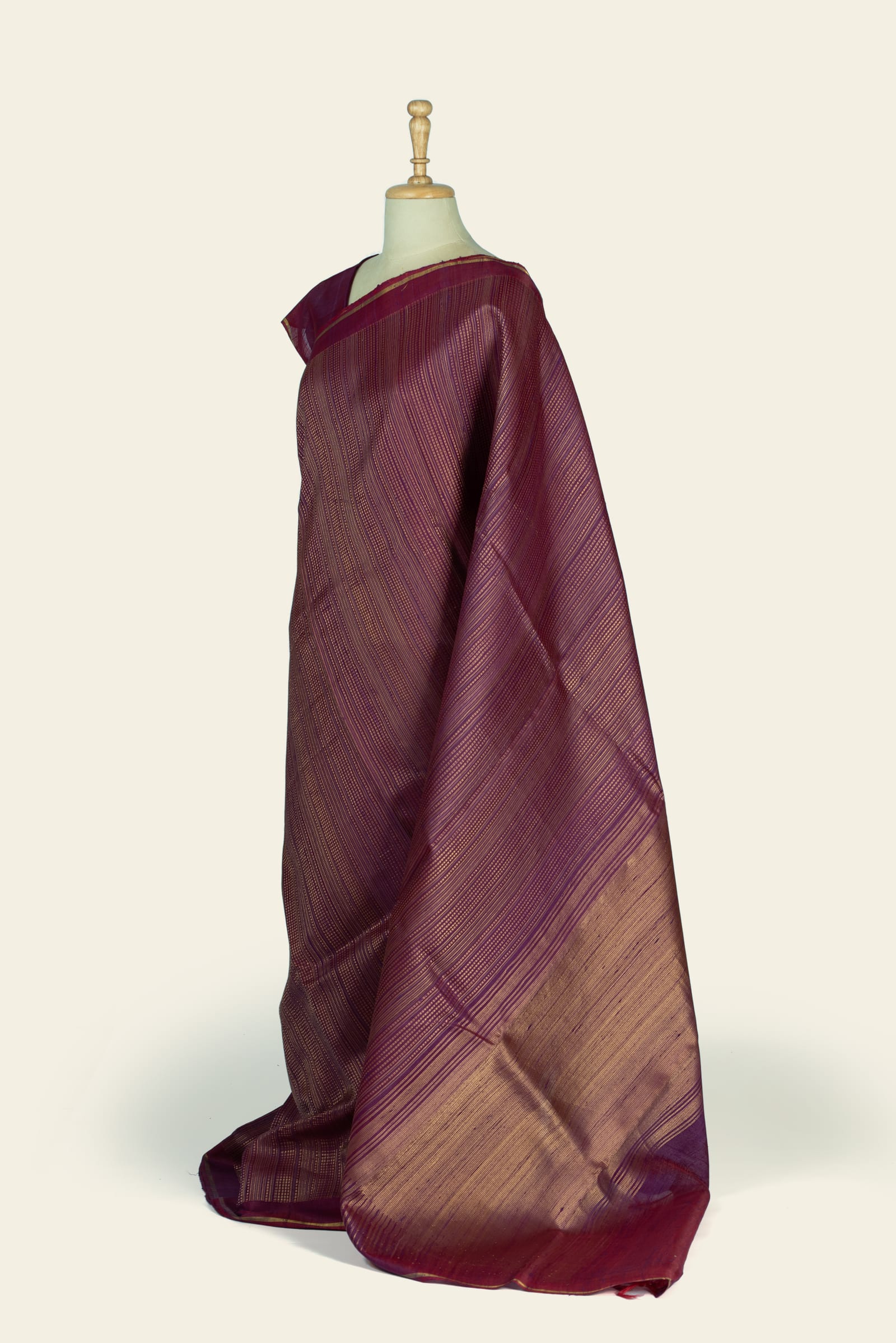 Side-angle view showing the saree's pallu and body with gold diagonal stripes and a broad gold-toned pallu section near the end.
