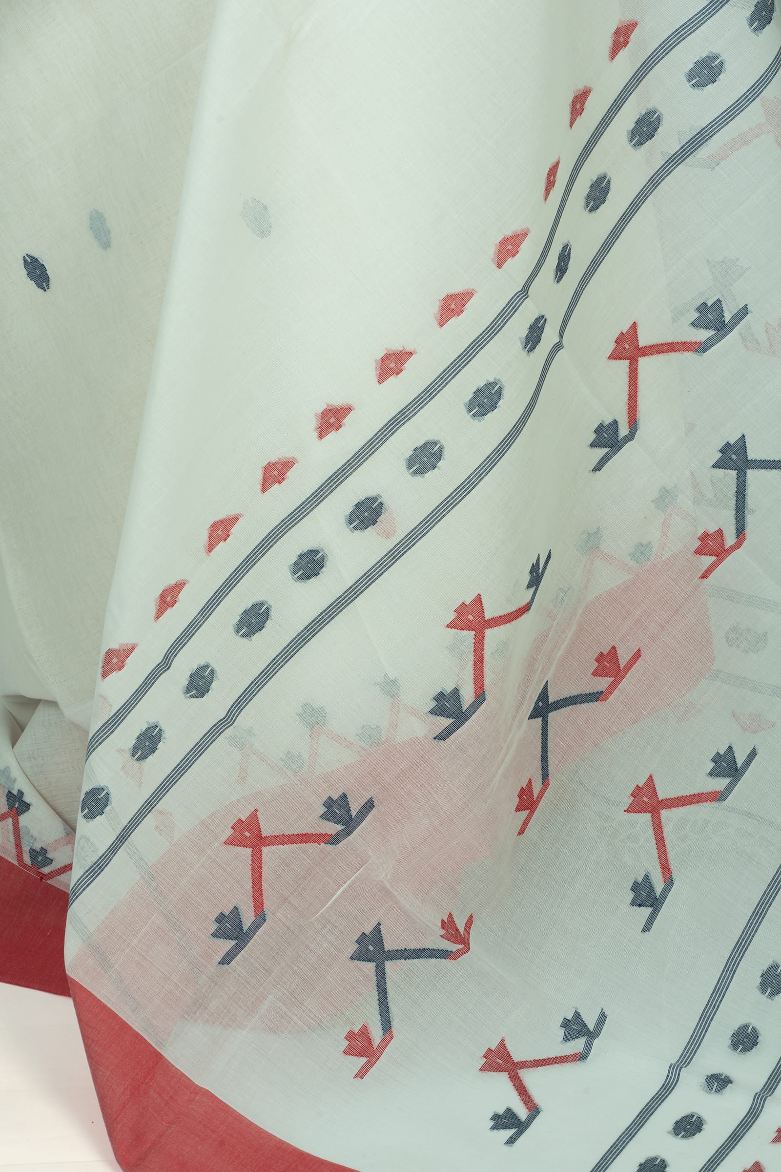 Close-up of the saree fabric showing the printed border details with coral and slate geometric motifs and a narrow double stripe.