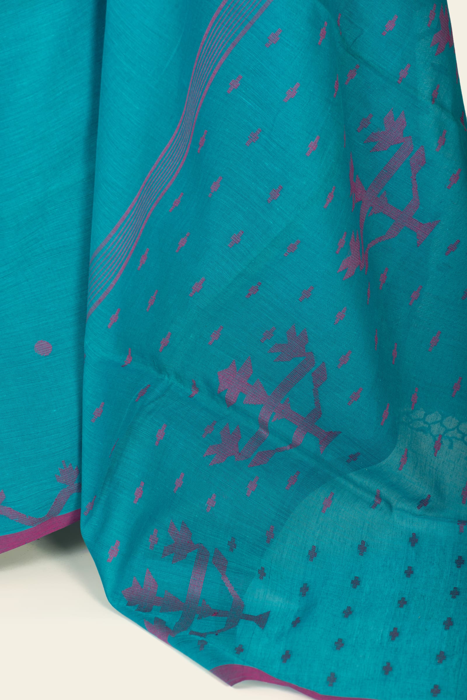 Detailed close-up of the saree pallu showing magenta foliate motifs and a pattern of small magenta marks on teal.