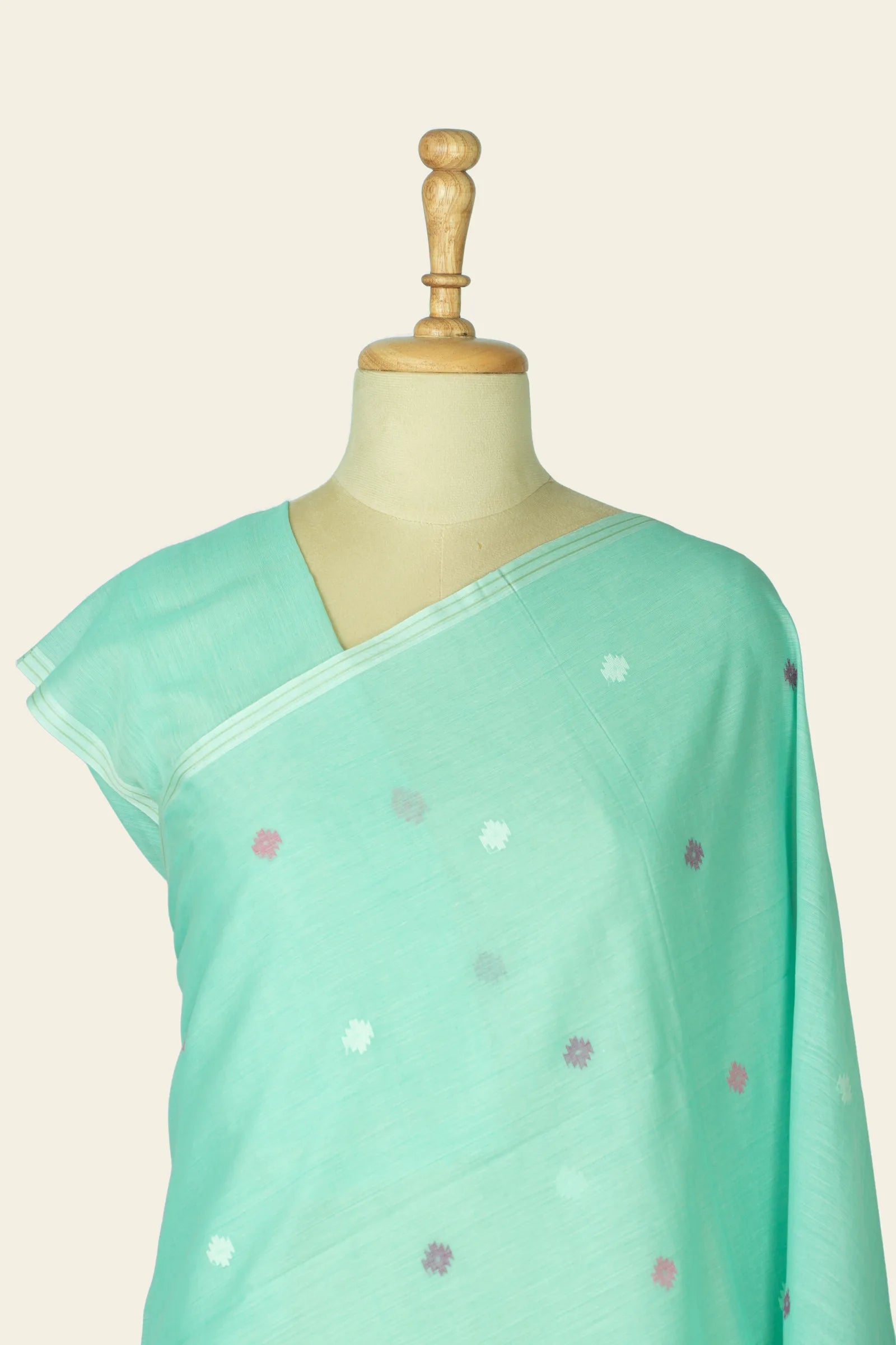 Close upper drape over a mannequin showing the saree neckline and scattered small motifs.