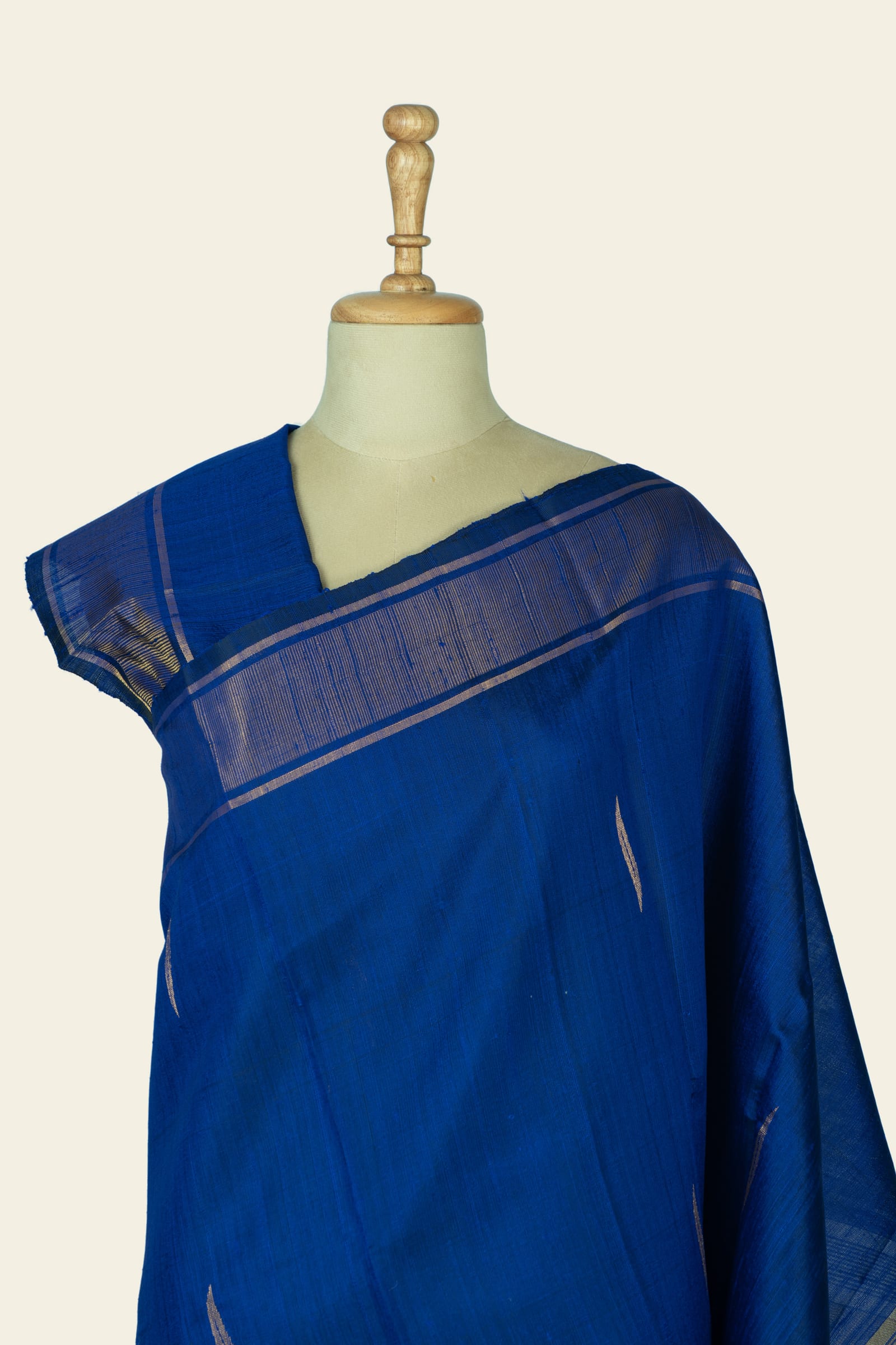 Close front view of the upper body and shoulder area showing the indigo blue saree with a fine striped temple-style border along the pallu and small vertical motifs on the body.