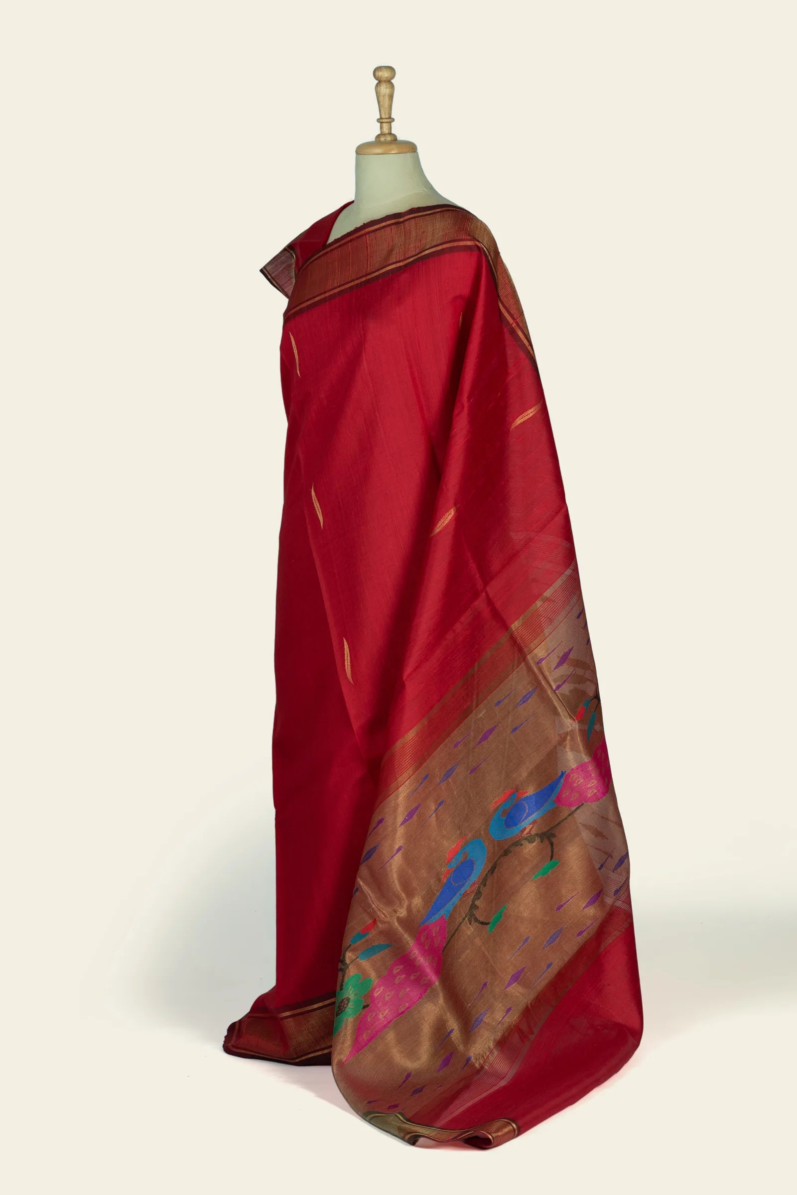 Side view showing the saree drape with a broad gold pallu that carries colorful woven motifs near the hem.