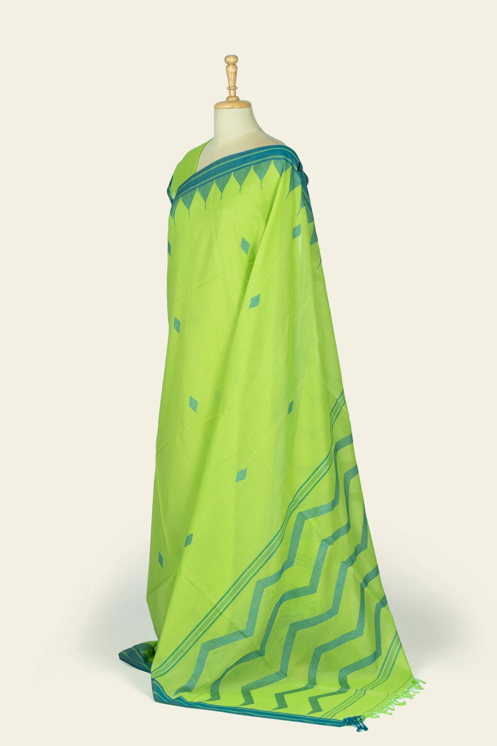 Angled side view showing the saree's lime green body with teal border and diamond motifs, and a longer view of the teal pallu at the hem.