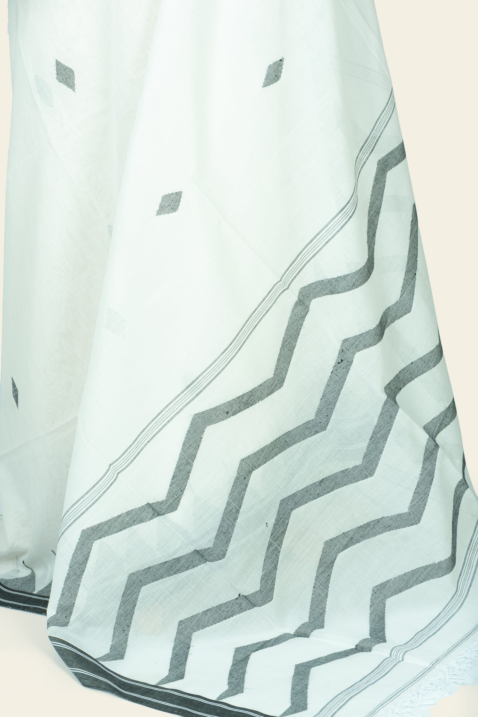 Detailed close-up of the pallu showing a bold black zigzag pattern and narrow striped border with fringed tassel edge.