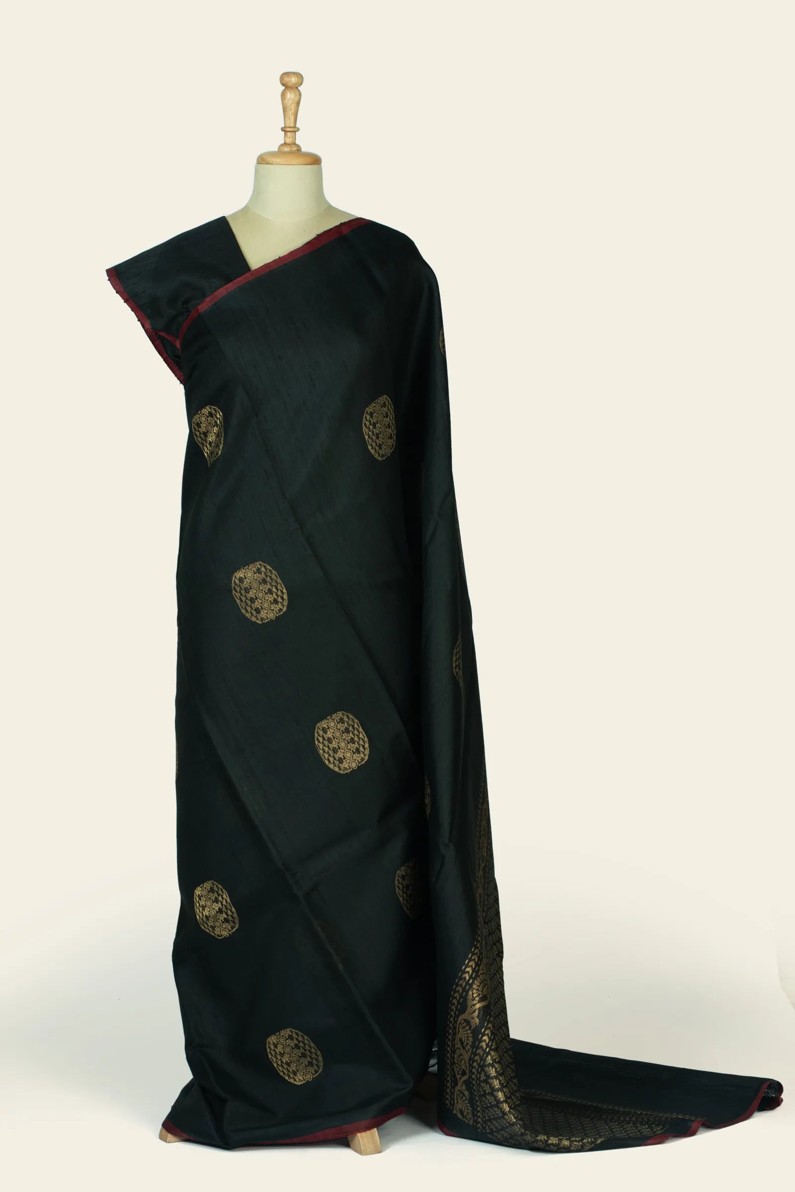 Full-length front drape of a black saree on a mannequin showing scattered round gold buta motifs