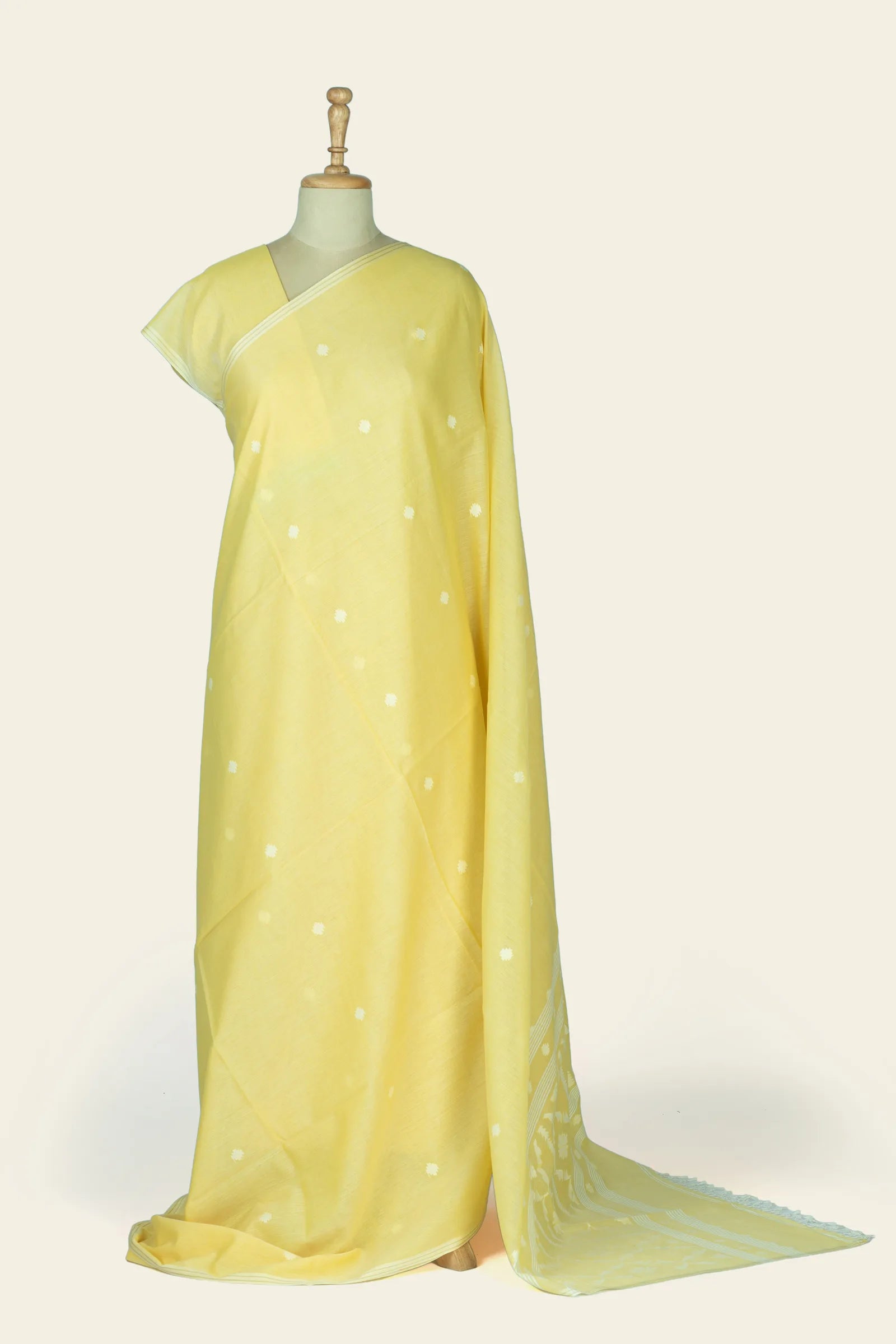 Full-length drape of a lemon yellow saree on a mannequin showing scattered cream floral butis across the body and the pallu trailing on the floor.