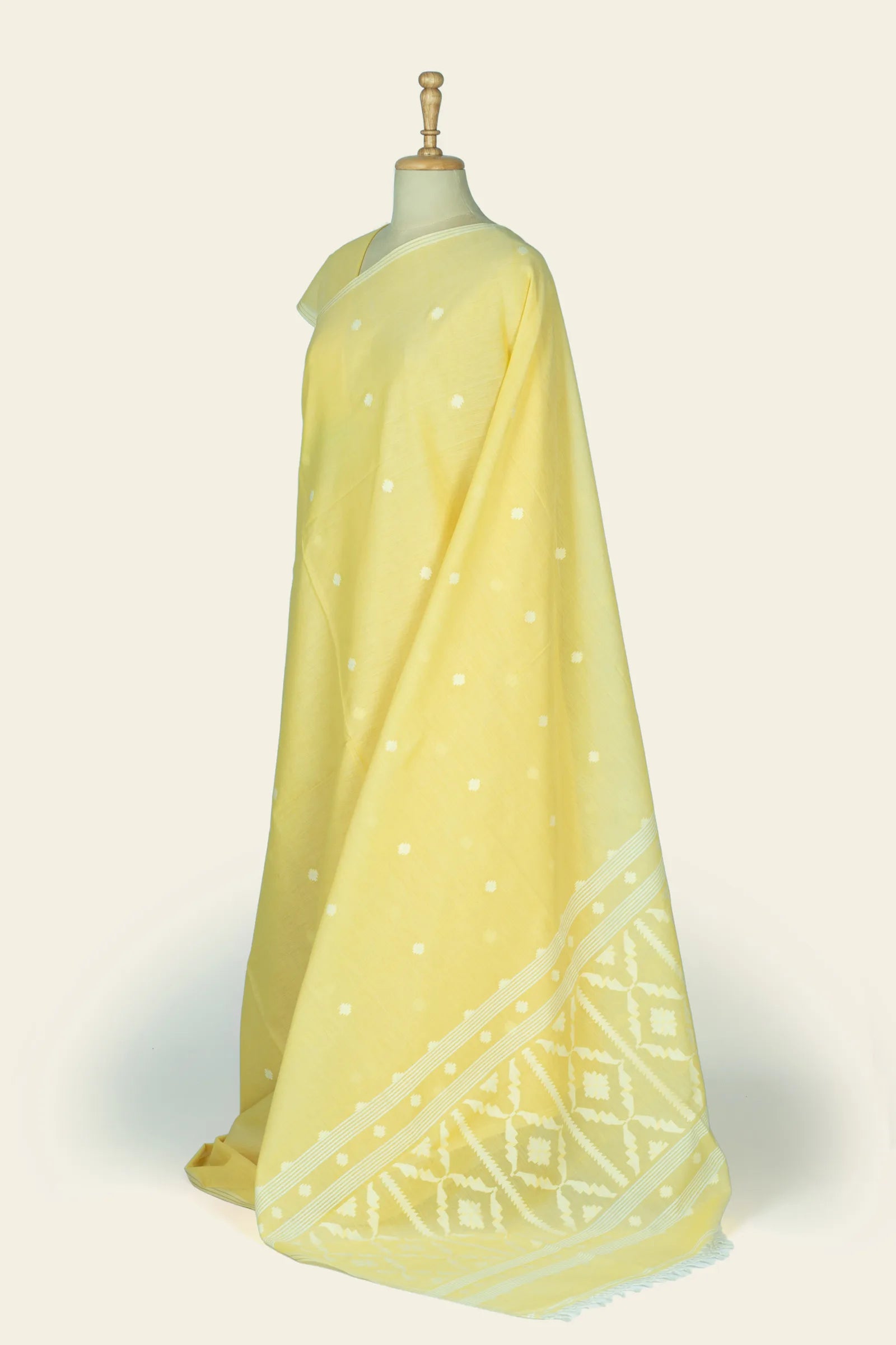 Front three-quarter view of the saree showing the body dotted with cream butis and a wide geometric patterned border on the pallu.