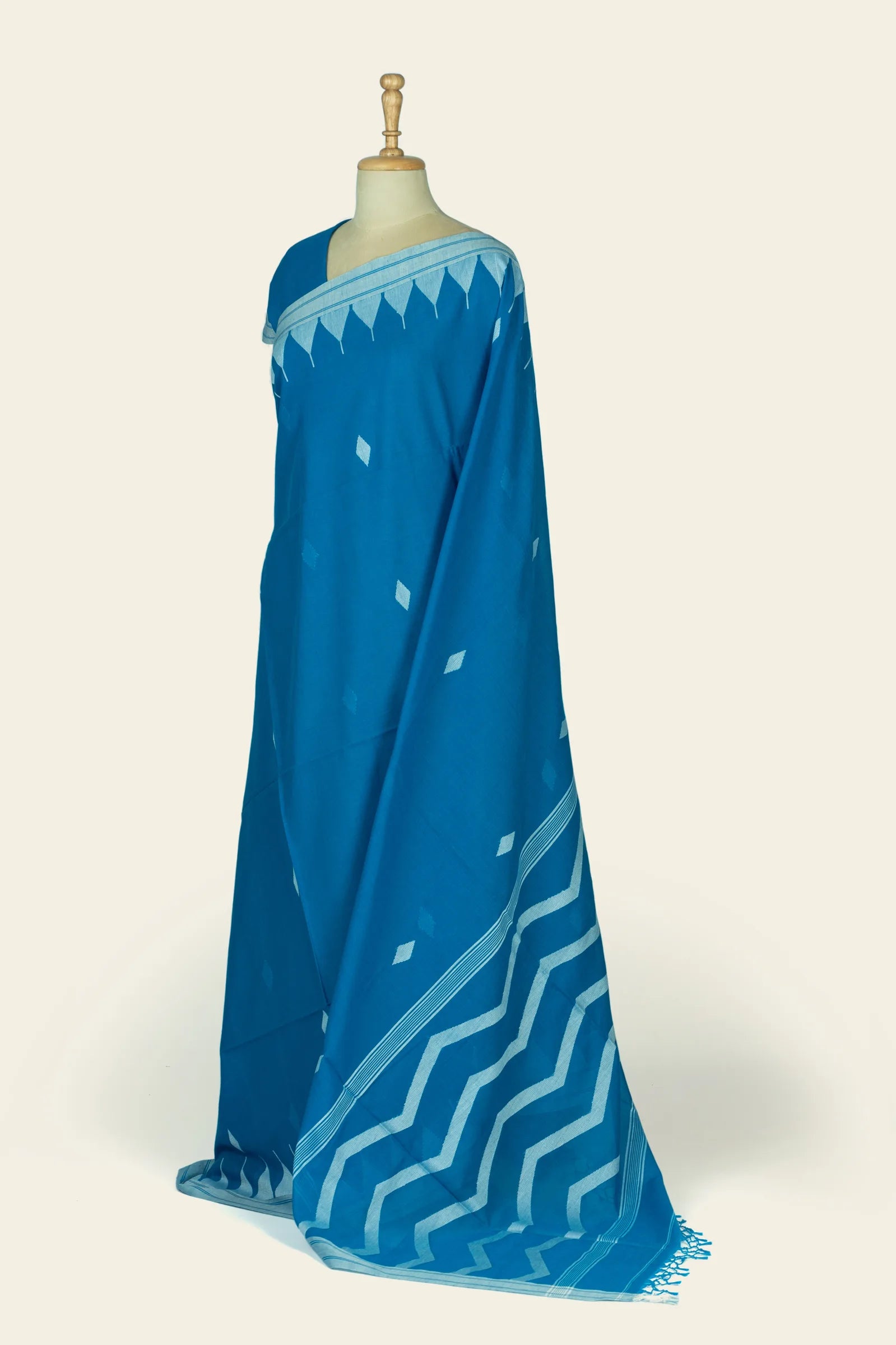 Side view of the saree drape showing the pallu with a wide pale-blue zigzag pattern and tasseled edge.
