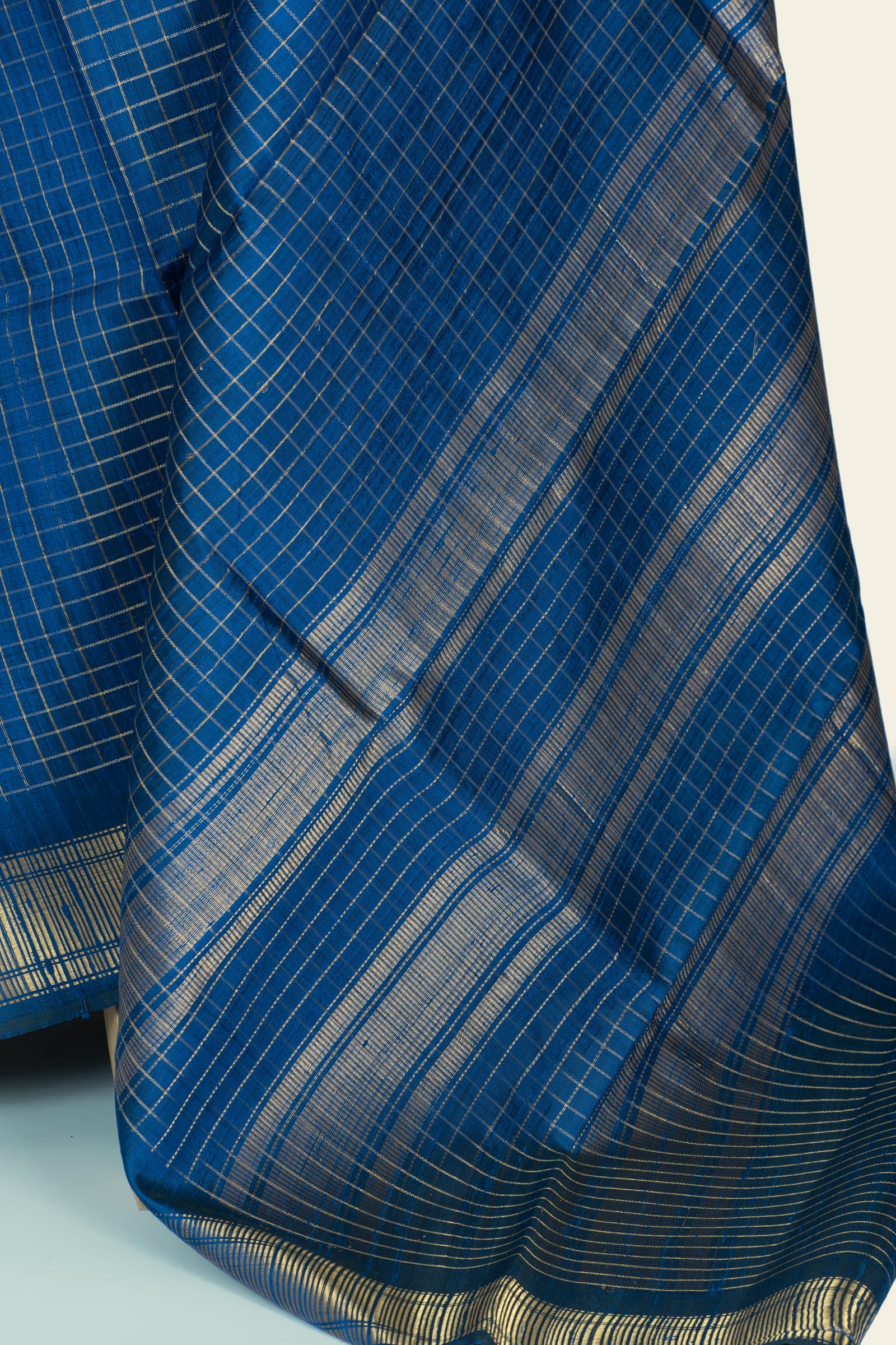 Detailed close-up of the saree fabric showing fine checked weave and the alternating metallic stripes on the pallu and border.