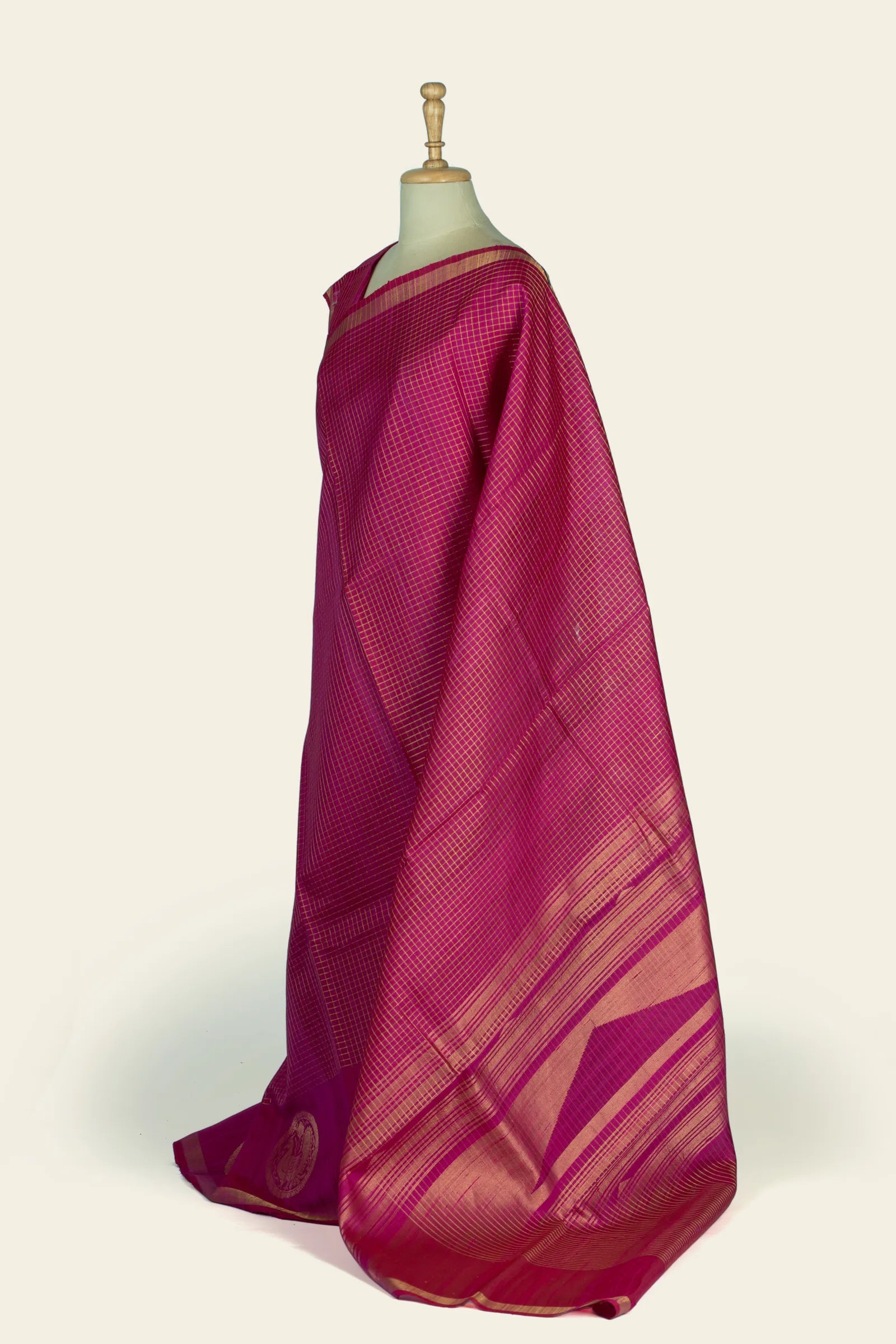 Side view of the saree draped on a mannequin, showing the checked body and the broad gold-striped pallu falling to the floor.