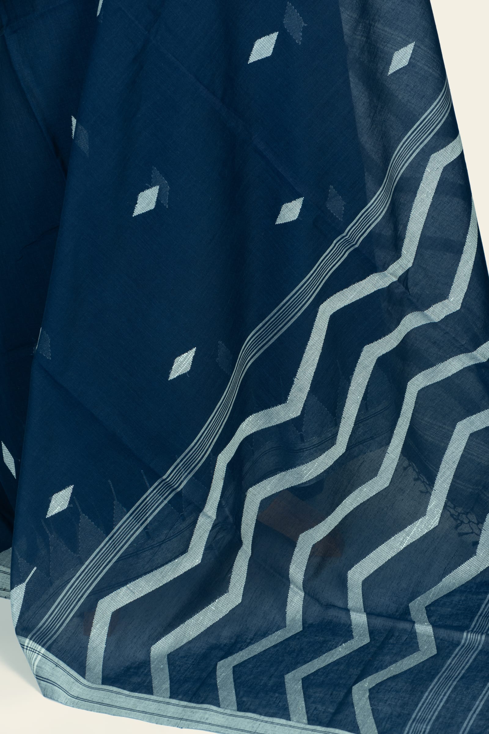 Detailed view of the saree pallu showing large zigzag bands in light blue against the indigo background and the woven striped selvedge.
