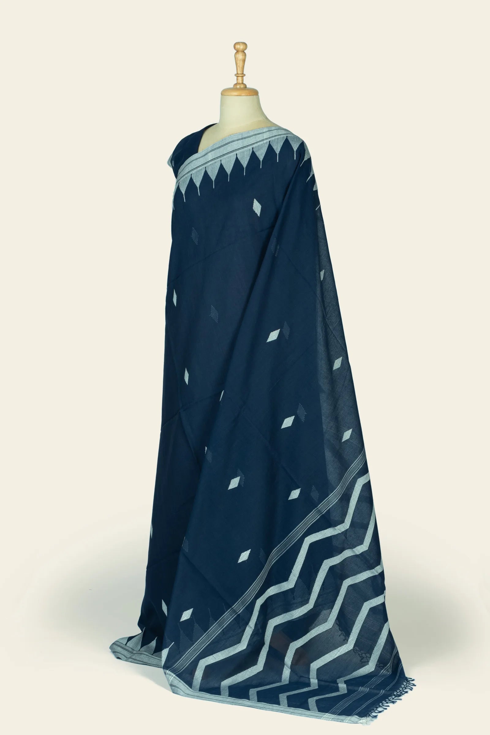 Side view of the saree draped on a mannequin showing the body motifs and the pallu with wide zigzag design near the end.