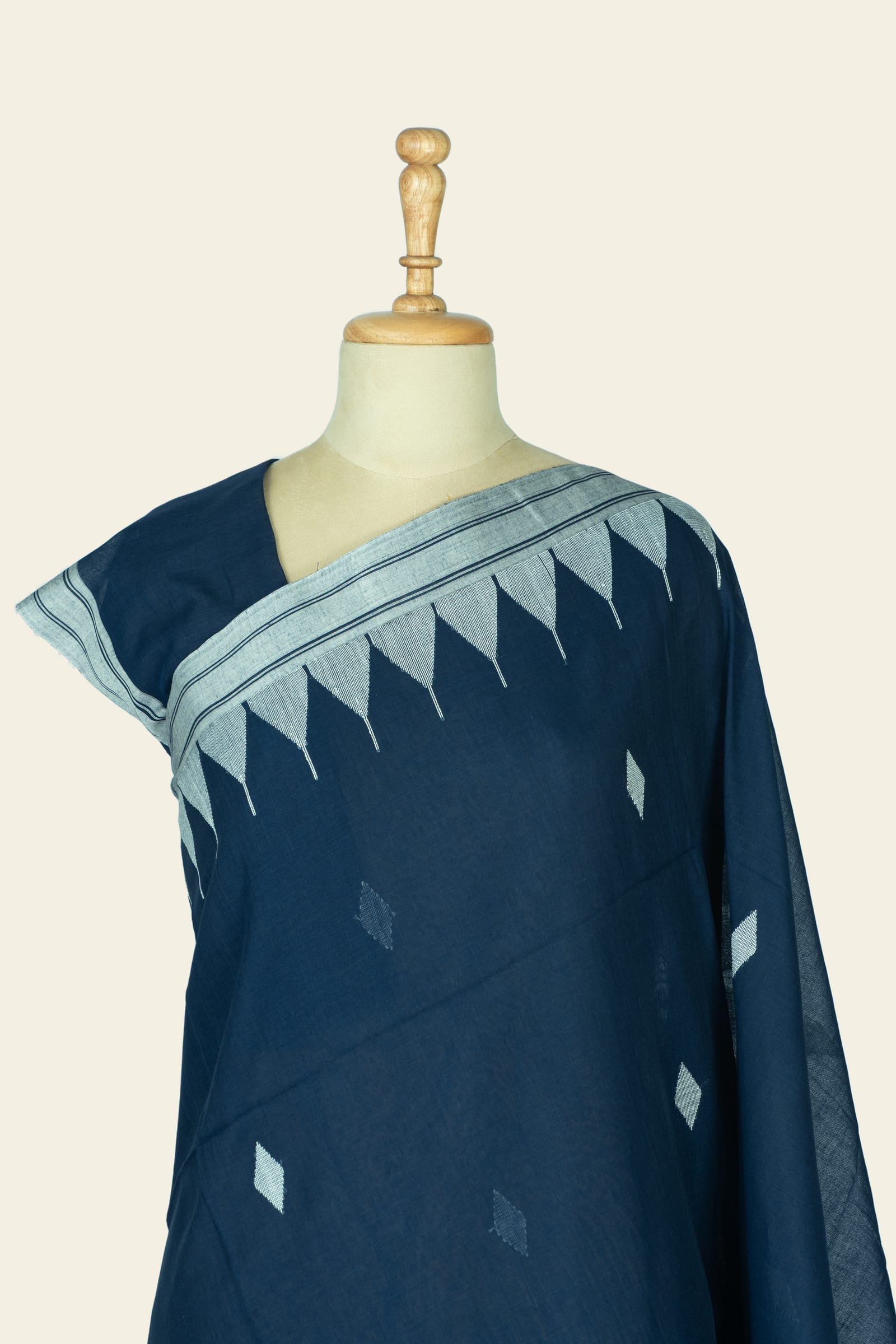 Close front view of the saree across the shoulder showing the woven triangular border along the top and small diamond motifs on the body.