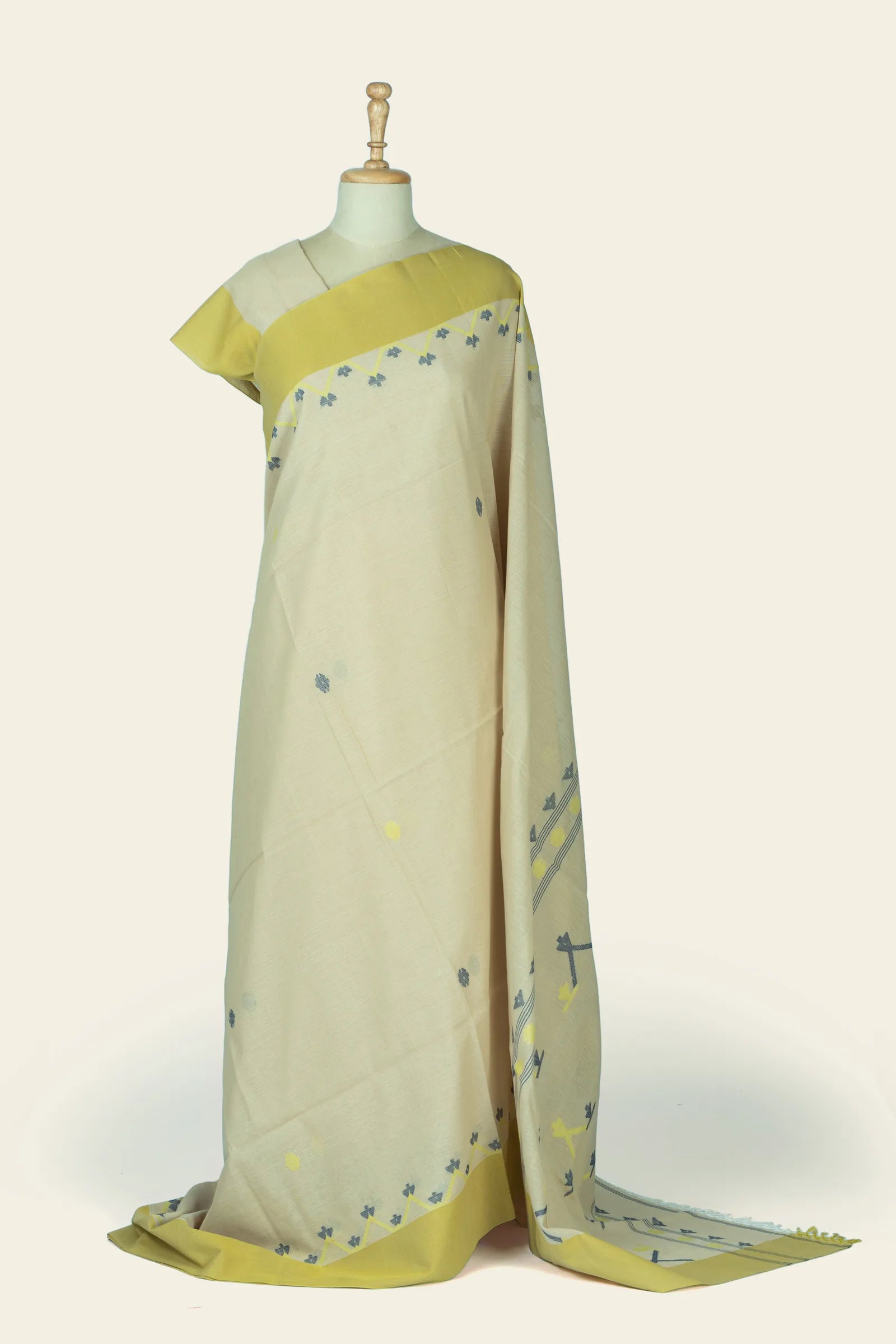 Full-length front drape of a cream saree with a wide lemon-yellow border and small scattered grey and yellow motifs.